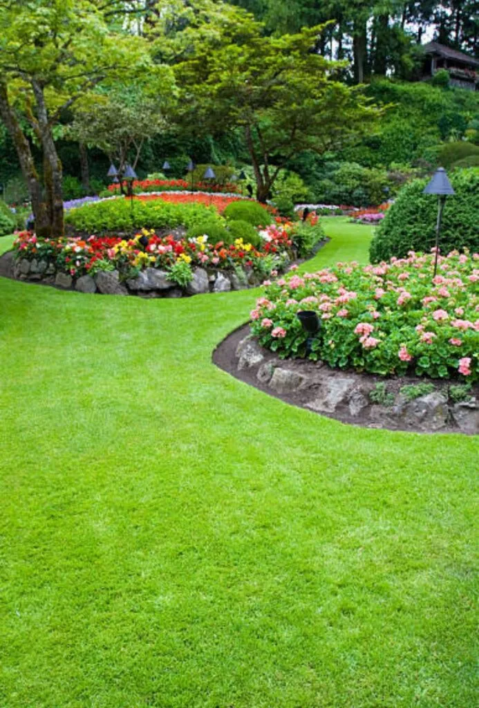 Landscaped garden with curved lawn edge, flower beds and pathway lighting