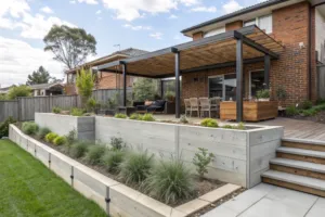 Concrete sleeper retaining walls supporting outdoor entertaining area with deck and pergola Central Coast property